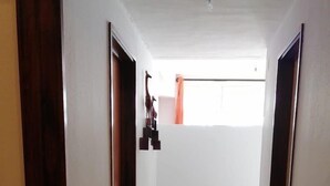 Un pasillo con suelo de baldosas, puertas de madera y una lámpara en el techo.