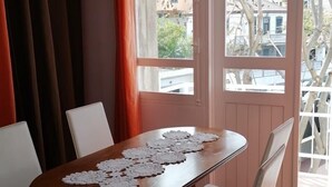 Un comedor con una mesa de madera, sillas blancas y copitos de encaje.