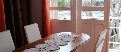 Un comedor con mesa de madera, sillas blancas y camino de mesa de encaje.