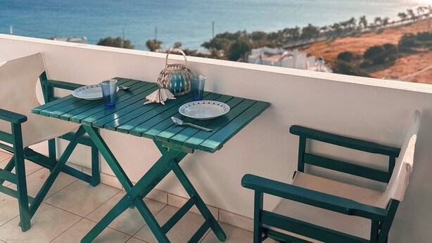 A balcony with a table and chairs, overlooking a coastal view with the sea and distant land. - Blue orison house Tinos for 5 persons with seaview (Tinos Regional Unit)