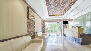 A spacious lobby with a beige leather sofa, a reception desk, and a patterned ceiling.