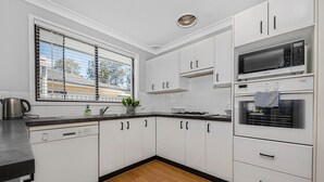 A modern kitchen with white cabinets, a Bosch dishwasher, a microwave, and a gas stove.