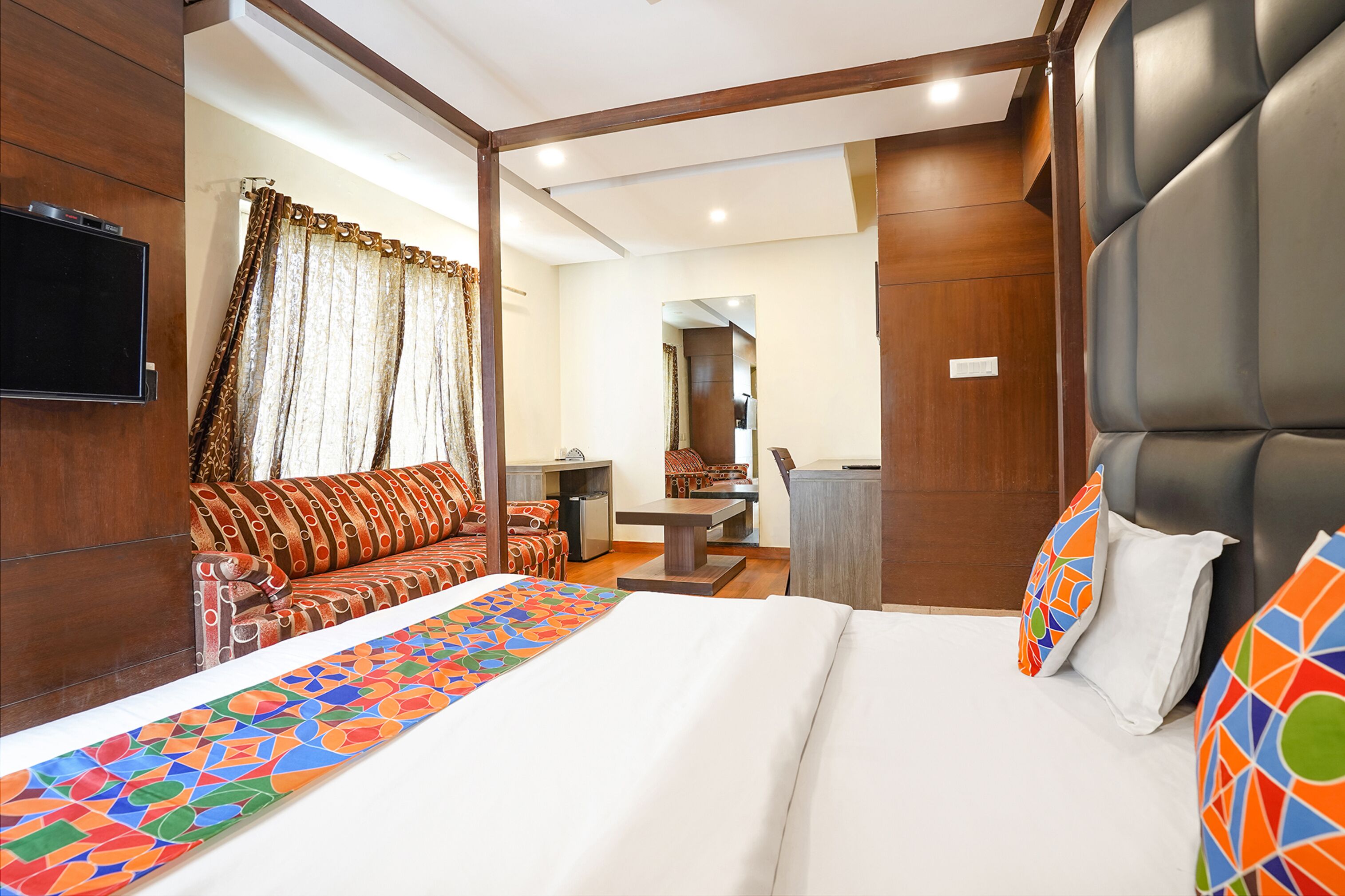 A hotel room with a bed, a sofa, a desk, and a television.