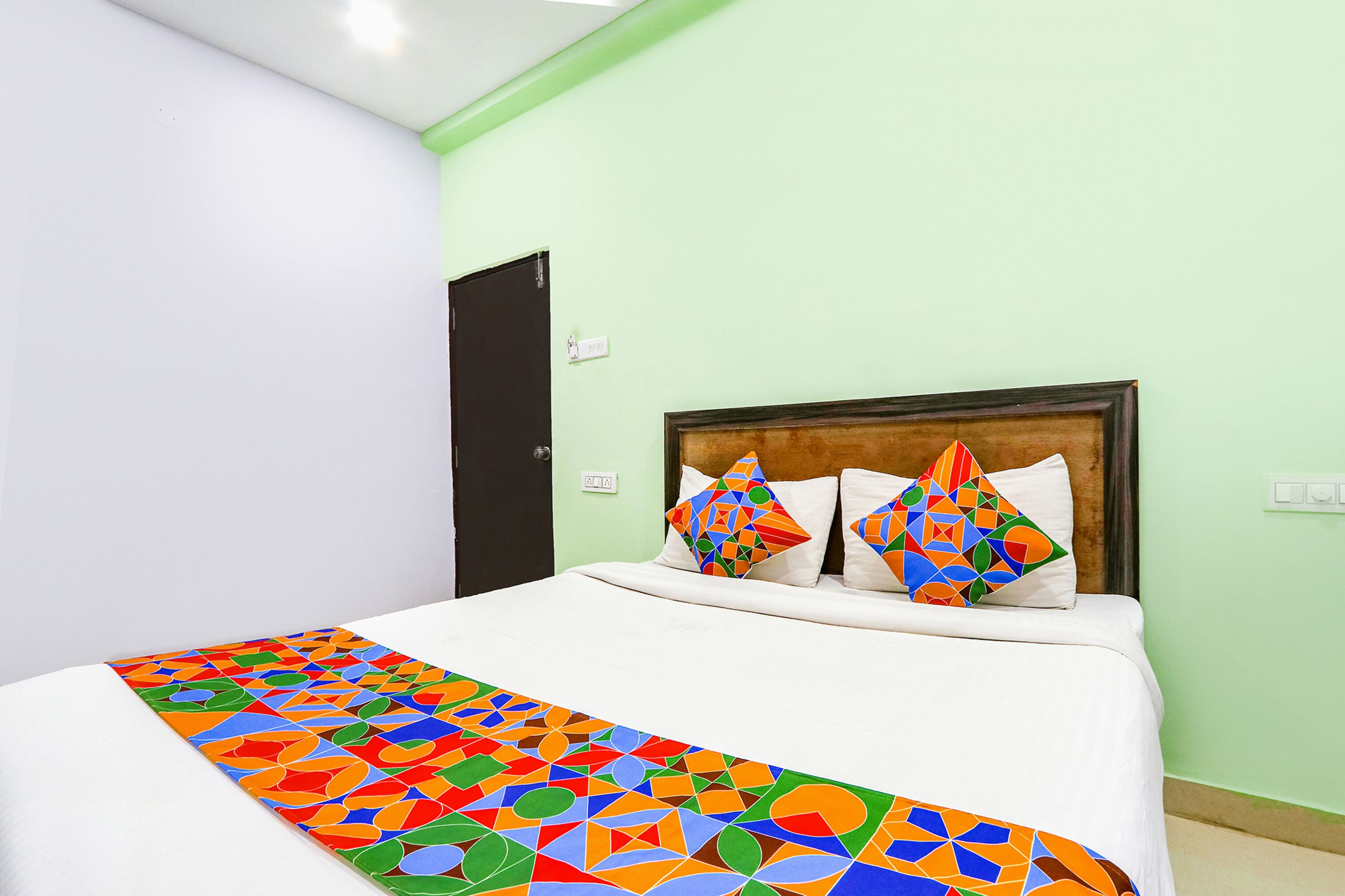 A neatly made bed with a colorful geometric-patterned bedspread and two decorative pillows.