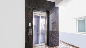 A hallway with a marble wall, a patterned floor, and a door with a glass panel. - Fabexpress Night Eye (Hyderabad)
