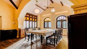 Comedor con techo alto, ventanas arqueadas y una mesa central dispuesta para comer.