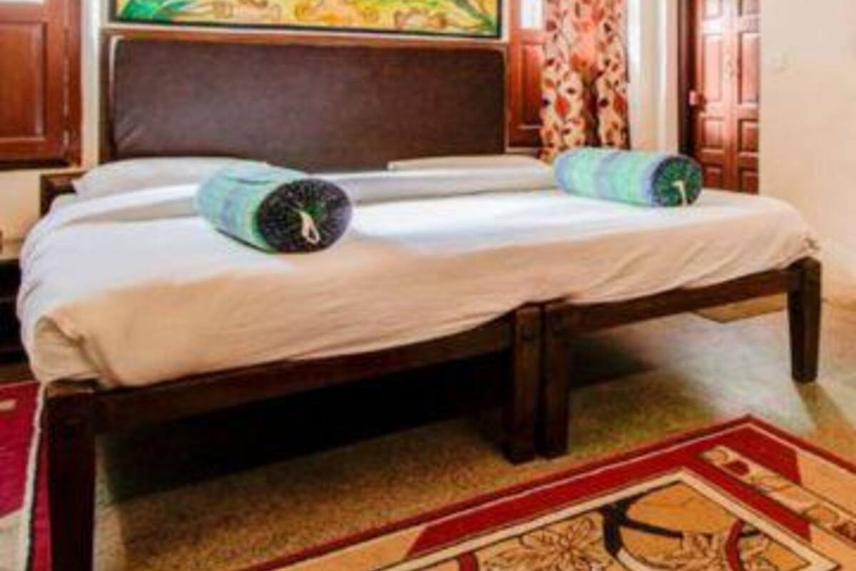 A bedroom with a large bed, a painting above the bed, and a wooden headboard.