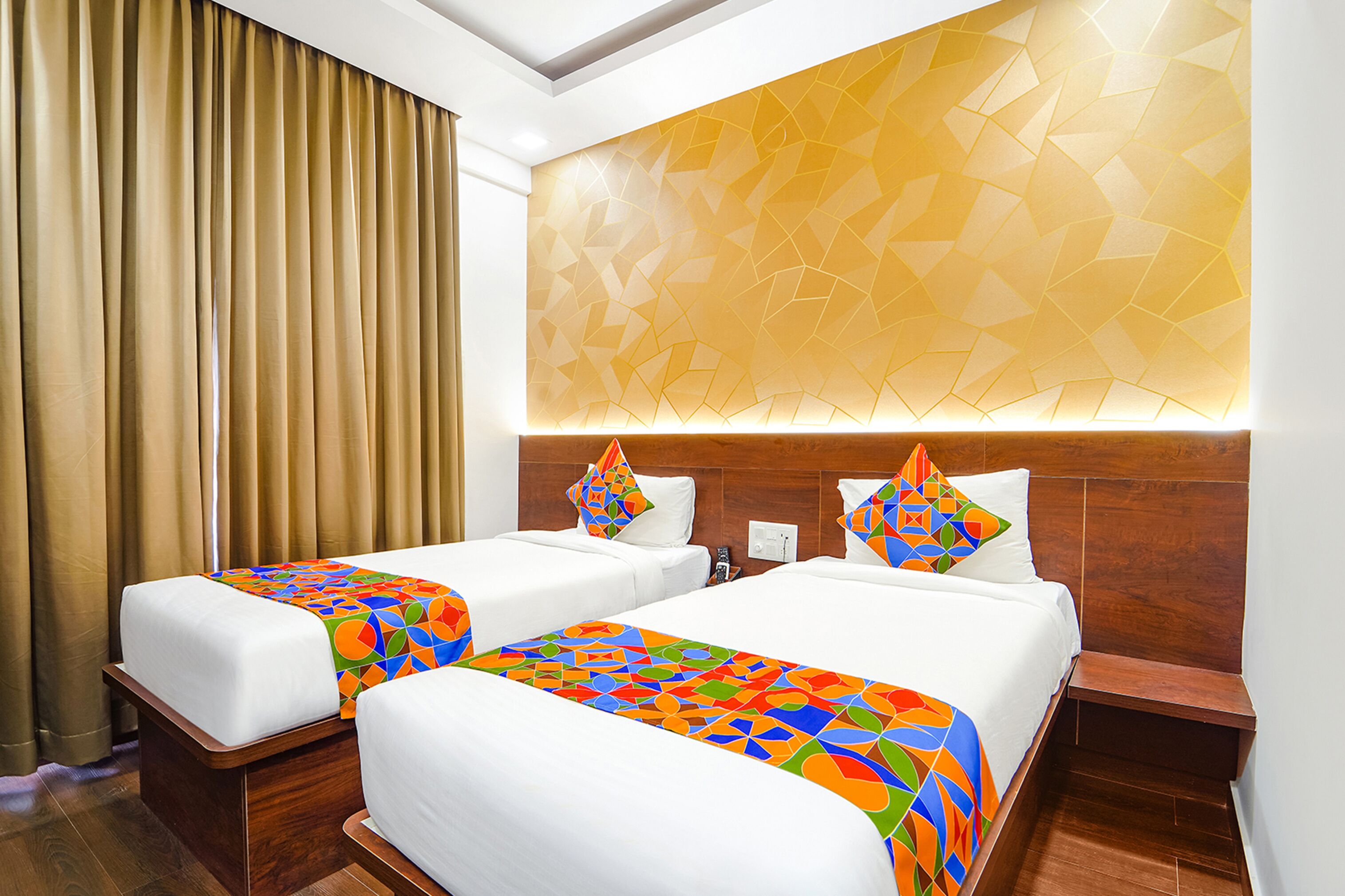 A hotel room with two beds, a geometric-patterned wall, and a wooden headboard.