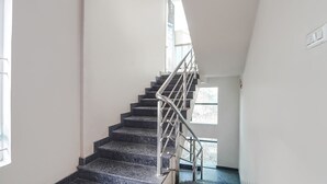 Una escalera con barandillas metálicas y vistas a un edificio cercano.