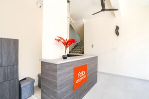 A reception desk with a 'fab express' logo, a potted plant, and a staircase in the background.