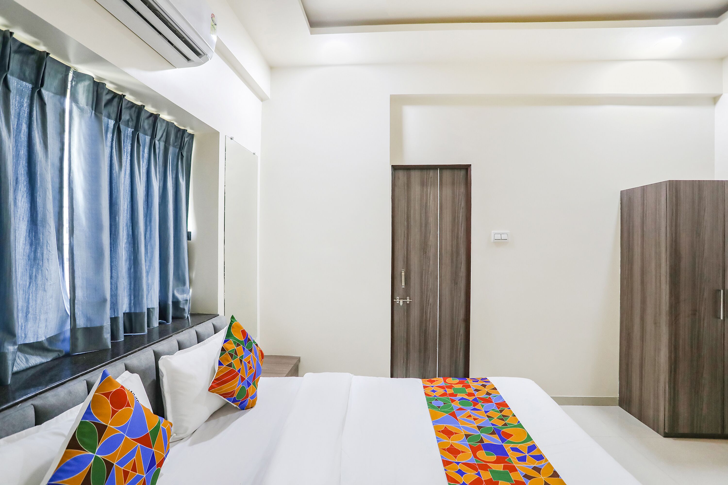 A bedroom with a bed, a wardrobe, a door, and curtains.