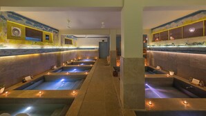 A spa area with multiple hot tubs, stone walls, and ceiling fans. - FabHotel Prime BT Wellness With Pool (Morjim)