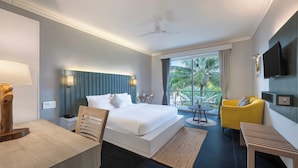 A modern hotel room with a large bed, a desk, a yellow armchair, and a television. - FabHotel Prime BT Wellness With Pool (Morjim)