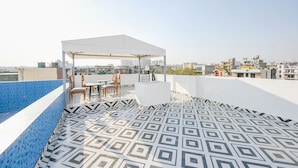 Une terrasse sur le toit avec un sol à motifs, un espace salon couvert et une vue sur le paysage urbain.