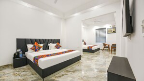 Une chambre d’hôtel moderne, dot ée d’un grand lit, d’un bureau, d’une chaise et d’un téléviseur fixé au mur.