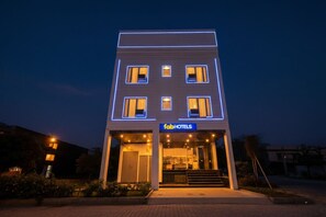 Un hôtel moderne à la façade sobre, doté de nombreuses fenêtres et d’une entrée bien visible, accessible par quelques marches.