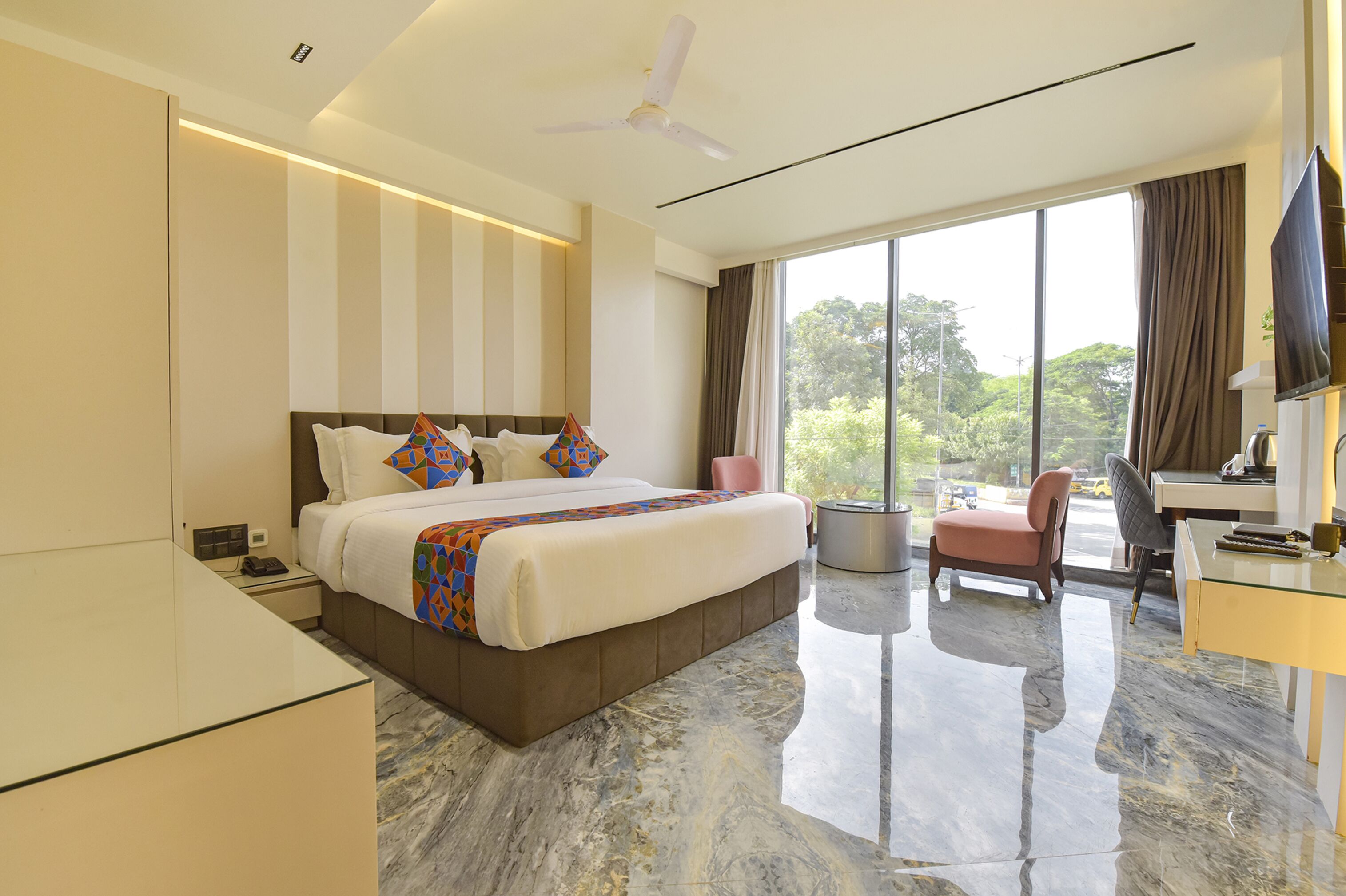 A modern hotel room with a large bed, a desk, and a chair.