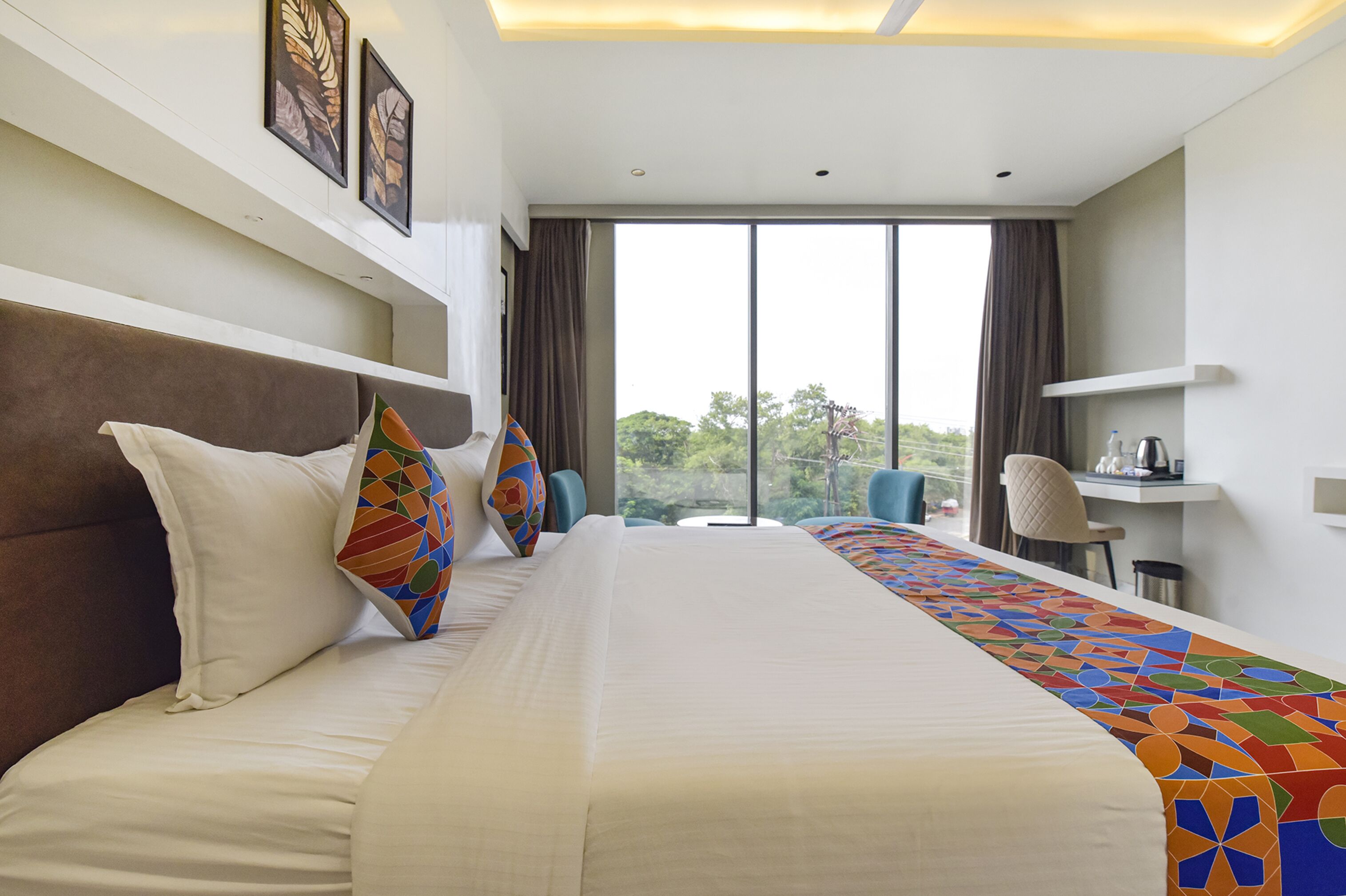 A hotel room with a large bed, a desk, and a view of the outdoors.