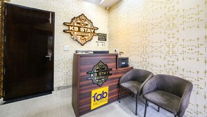 A reception desk with a 'fab hotels' sign, a K9 stay sign, and a reception area with a dark wooden door and a grey chair. - Fabhotel K9 Stay (Ludhiana)