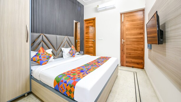 A modern hotel room with a bed, a TV, and a wooden wardrobe. - Fabhotel K9 Stay (Ludhiana)