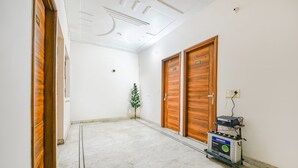 A hallway with wooden doors, a small Christmas tree, and a power generator. - Fabhotel K9 Stay (Ludhiana)