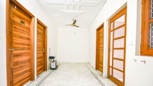 A hallway with wooden doors, a ceiling fan, and a white floor. - Fabhotel K9 Stay (Ludhiana)