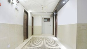 A hallway with a ceiling fan, a vent, and a door with a number plate. - Fabexpress Lotus Palace (New Delhi)