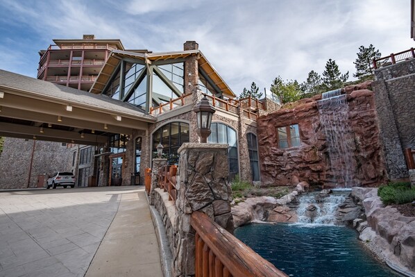 A modern hotel with a large entrance, a pool area with a waterfall, and a multi-story building with balconies. - Ski in/out at Westgate, 1BR Condo, Resort amenities, Multiple Pools, Onsite Spa, & Restaurant 4504A (Park City)