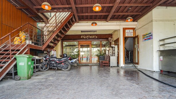 A hotel lobby with a staircase, a reception desk, and a sign indicating floor rooms. - Fabexpress Elegant Residency (Chennai)