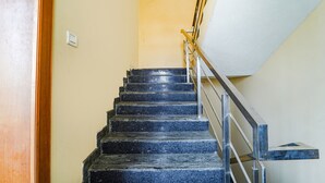 A staircase with black steps and a metal railing. - Fabexpress Elegant Residency (Chennai)
