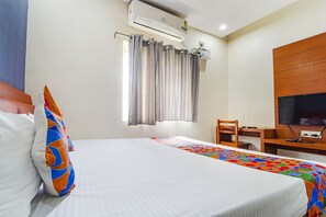 Une chambre d’hôtel équipée d’un lit, d’un bureau avec un ordinateur, d’une télévision et d’un appareil de climatisation.