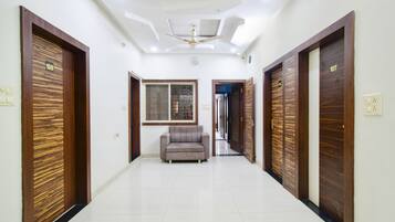 A hallway with two doors labeled 108 and 107, a grey sofa, and a ceiling fan.