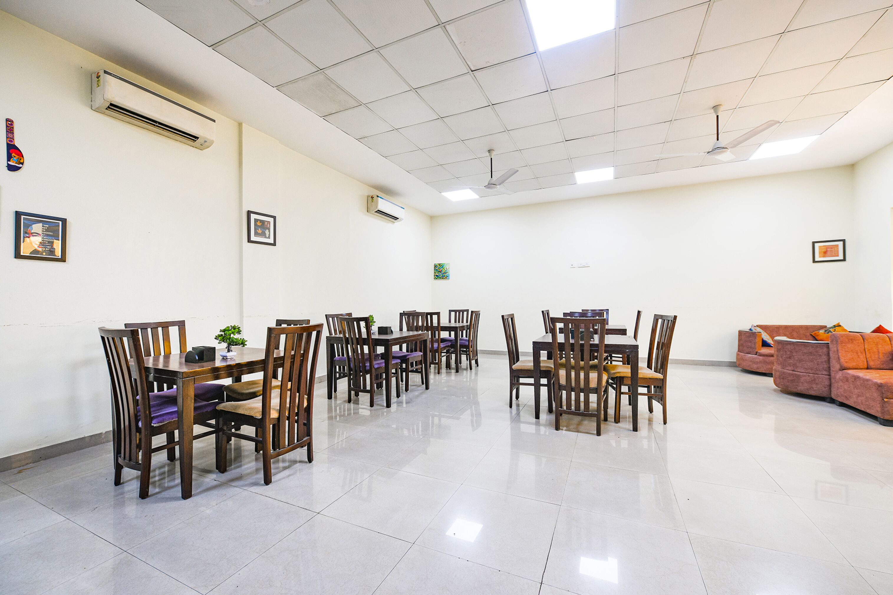 A spacious room with a long table and chairs, air conditioning units, and a ceiling fan.