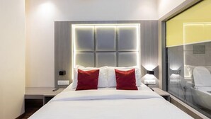 A modern hotel room with a large bed, a headboard with illuminated panels, bedside lamps, and a large window with a view. - Fabexpress Green House (Mumbai)