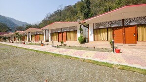A row of hotel rooms with individual entrances, each with a small garden area and a potted plant.