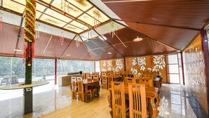 A spacious hall with wooden furniture, a high ceiling with a skylight, and a decorative wall with leaf patterns.