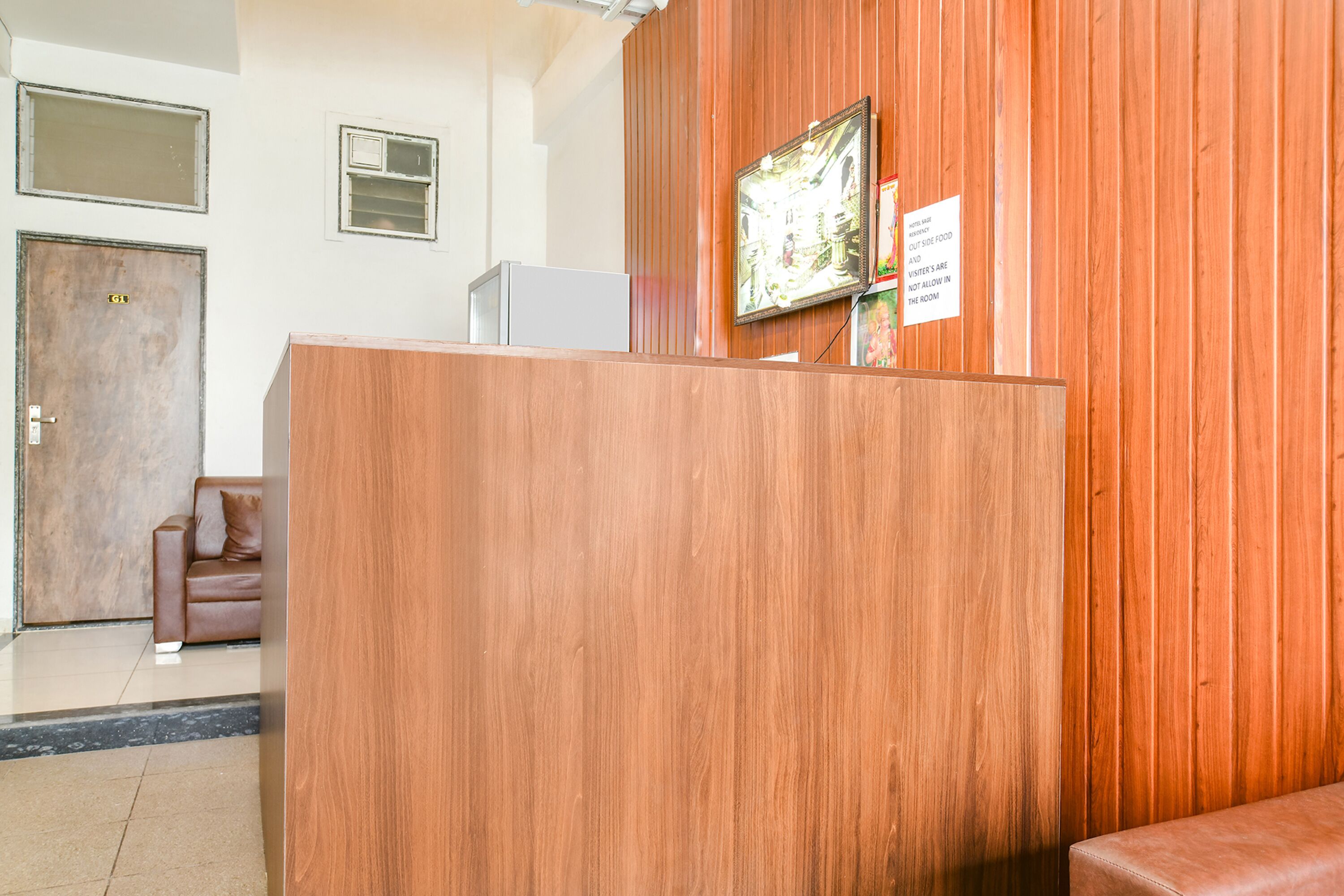 A reception area with a wooden reception desk, a framed picture on the wall, and a sign indicating no outside food.