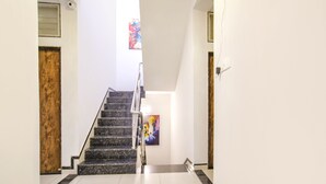 A staircase with a handrail, a wooden door, and a painting on the wall. - Fabhotel Sage Residency (Indore)