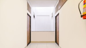 A hallway with a tiled floor, wooden doors, and a fire extinguisher on the right. - Fabhotel Sage Residency (Indore)