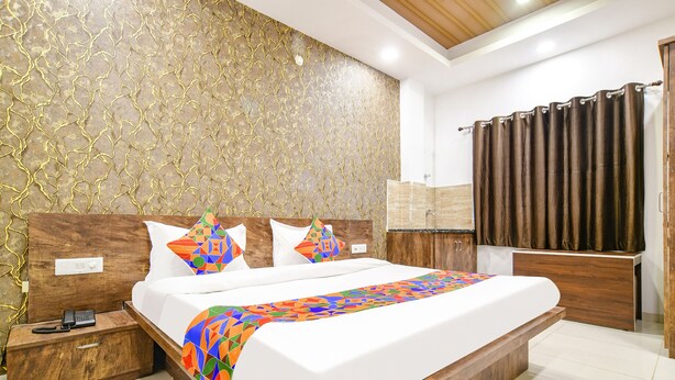 A modern bedroom with a large bed, wooden headboard, and a patterned wall. - Fabhotel Sage Residency (Indore)