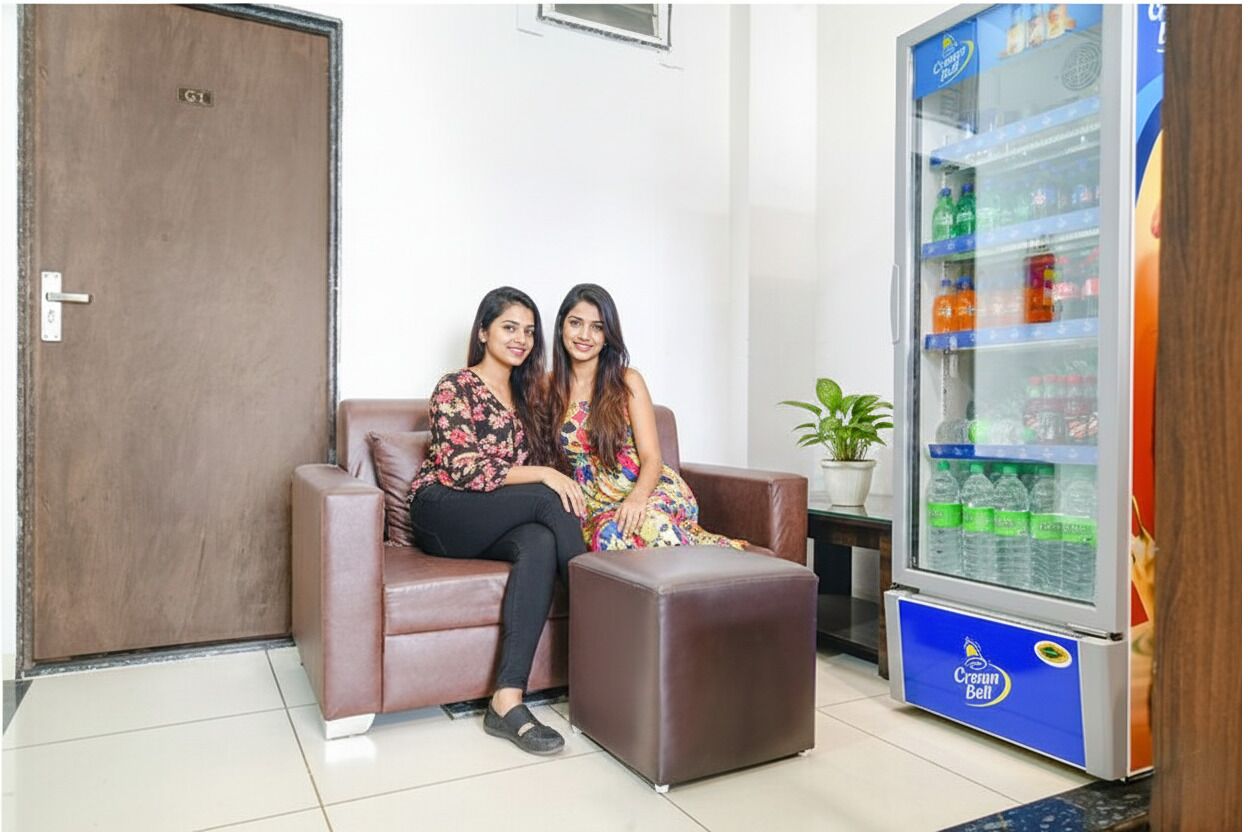A room with a brown leather sofa, a small ottoman, and a refrigerator stocked with beverages.