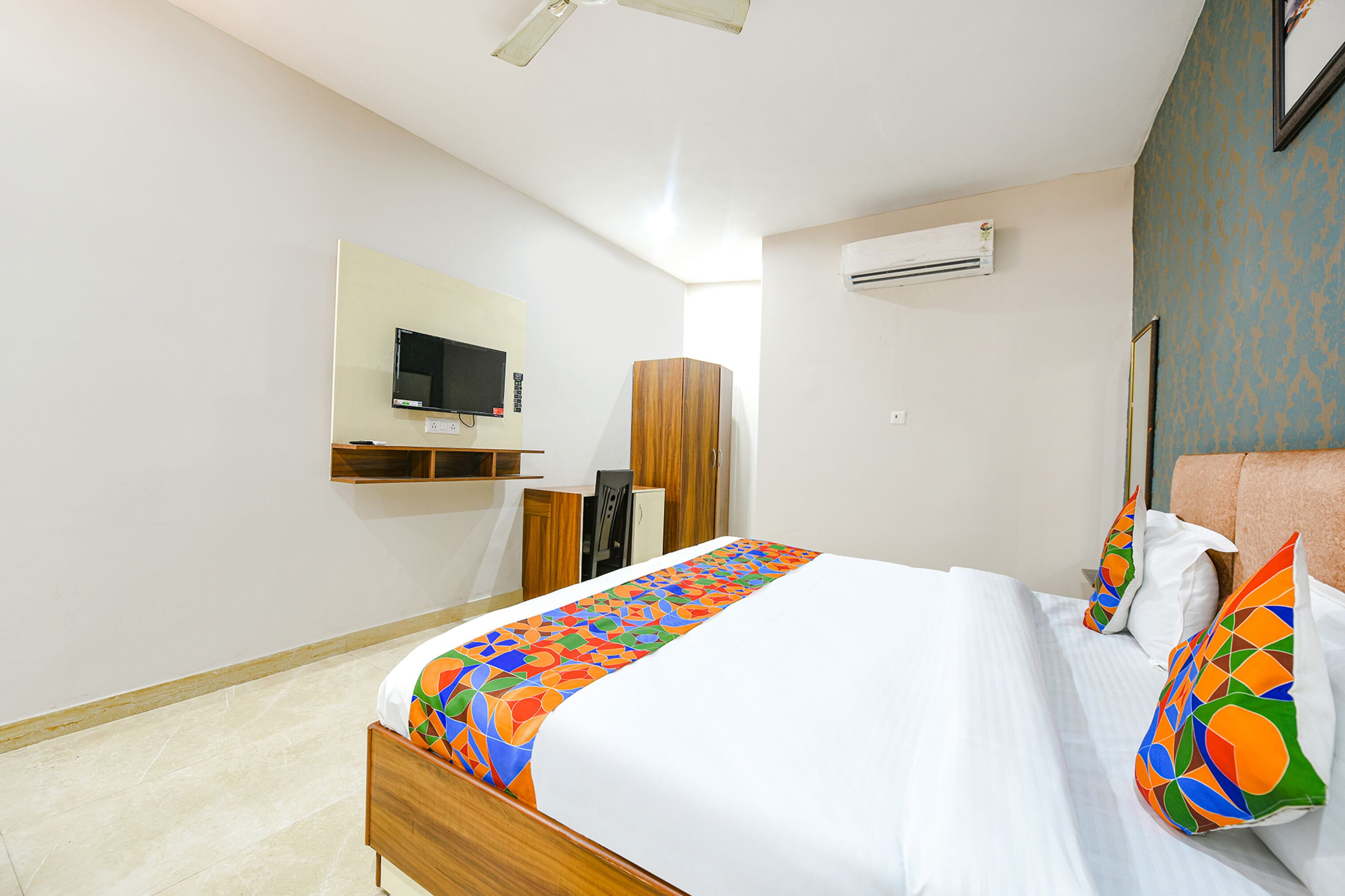 Ein Hotelzimmer mit Bett, Wandfernseher, Kleiderschrank und Klimaanlage.