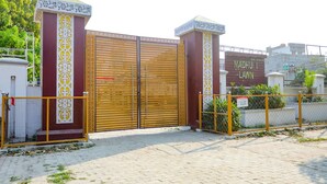 Una entrada con reja, protegida por una puerta metálica decorativa y un letrero que dice "MADHU LAWN".