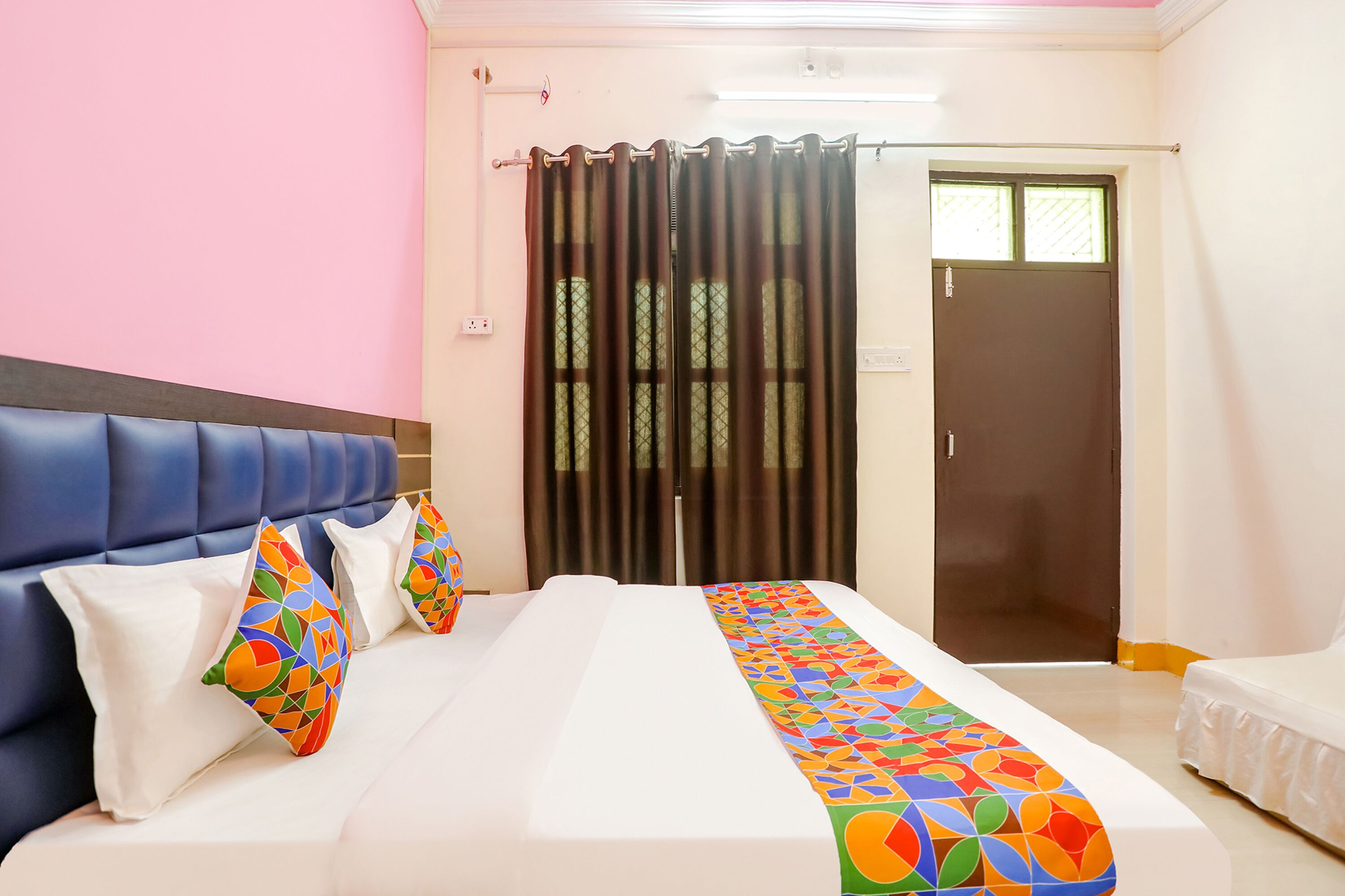Una habitación de hotel con una cama, cabecera azul y colcha colorida.