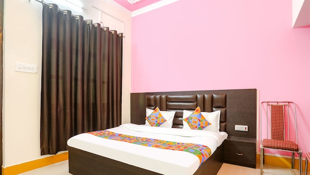 Un dormitorio con cama, mesita de noche, silla y cortina.