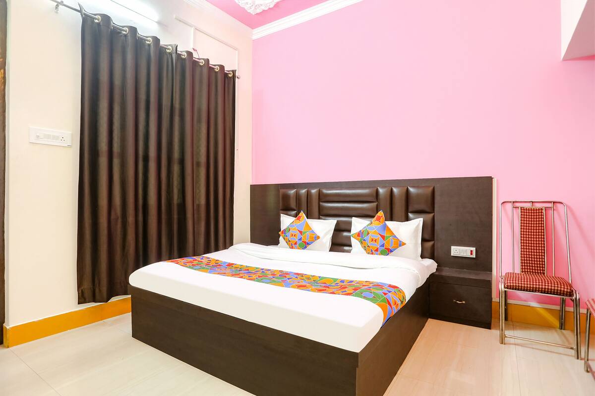 A bedroom with a bed, a nightstand, a chair, and a curtain.