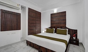 A bedroom with a large bed, wooden headboard, and a nightstand with a vase. - Fabhotel Sky Heights (Jaipur)