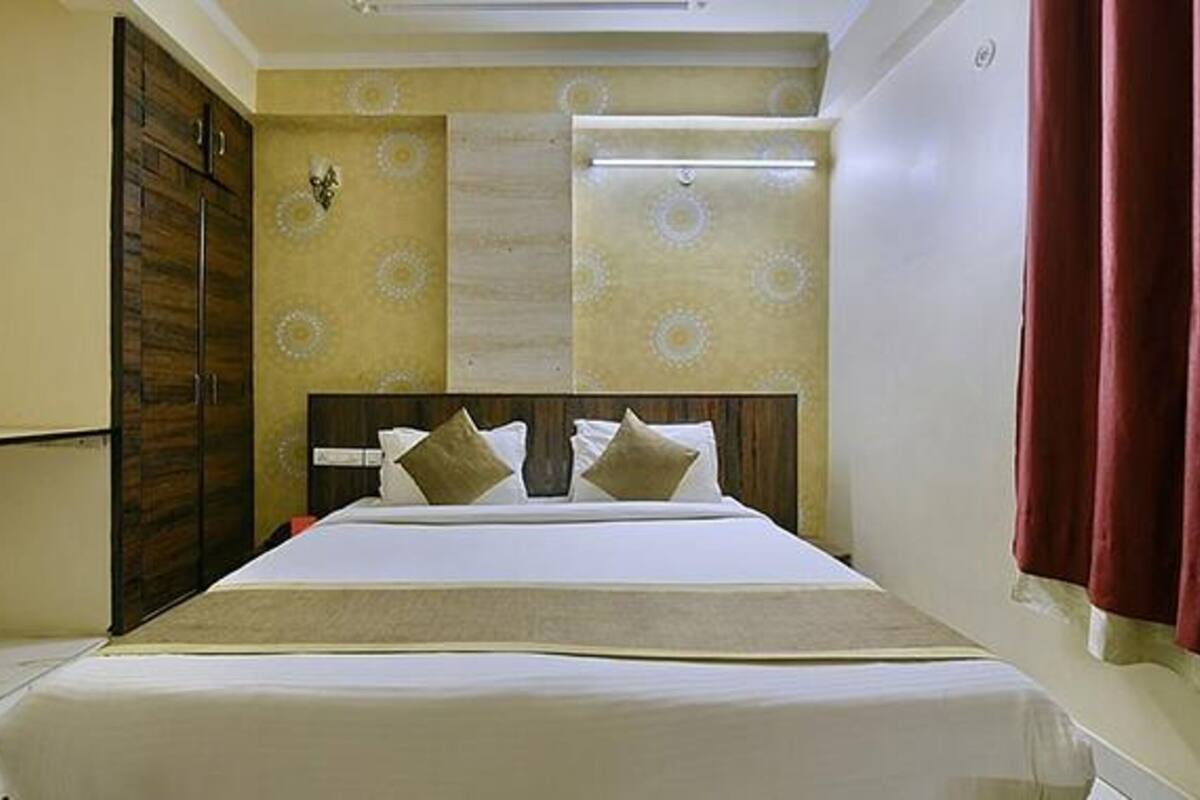 Une chambre d’hôtel avec un lit, une armoire et une fenêtre avec des rideaux.