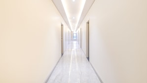 A long, narrow hallway with a polished floor and recessed lighting.