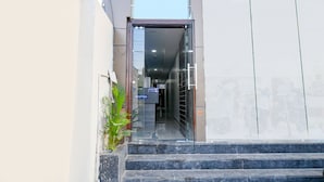 A hotel entrance with a reception desk, a staircase, and a potted plant.